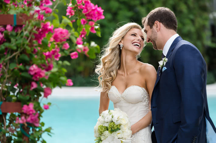 Bride and groom laughing next the pool just after their first look at the Miami Beach Edition