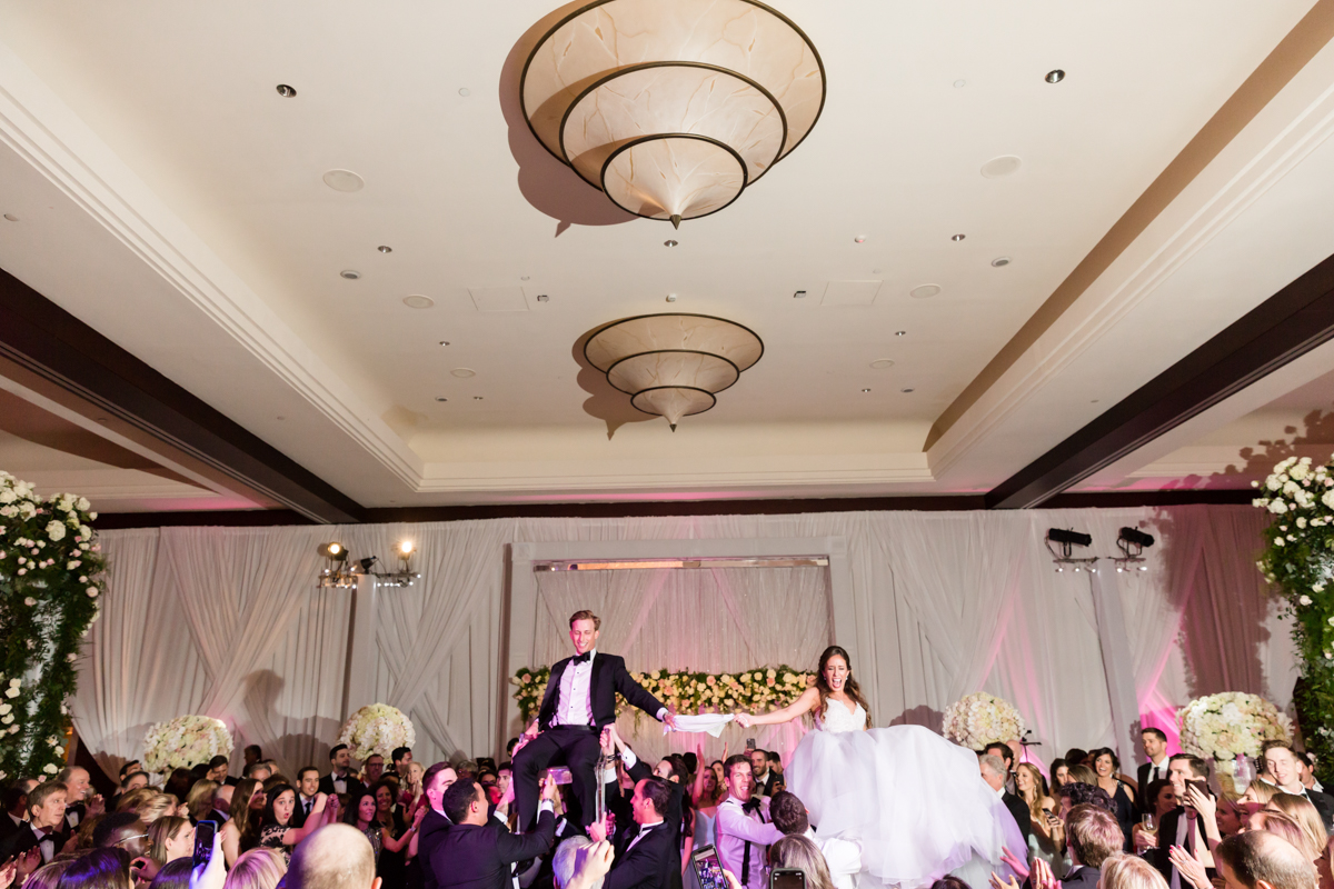 Bride and groom are lifted in chairs during hora at their wedding Mandarin Oriental on Brickell Key.
