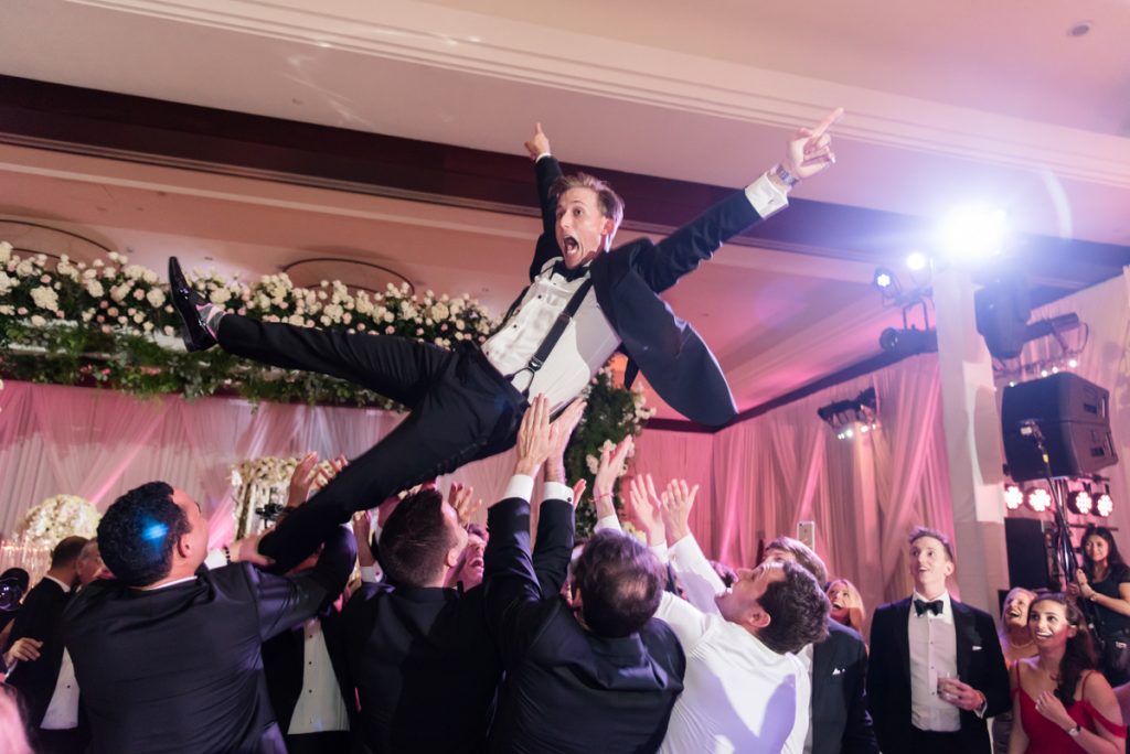Groom being thrown in the air during a wedding reception