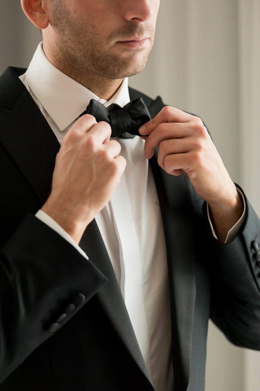 A groom adjusts his bowtie during preparations at the Miami Beach Edition.