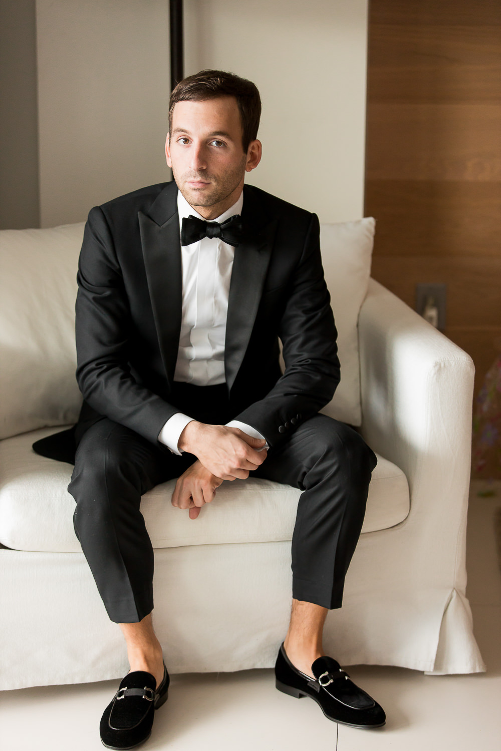 A groom in a tuxedo poses for a portrait in his suite at the Edition on Miami Beach.
