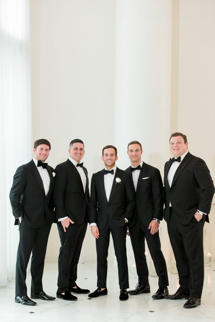 Groomsmen in black tuxedos during a group portrait at the Miami Beach Edition.