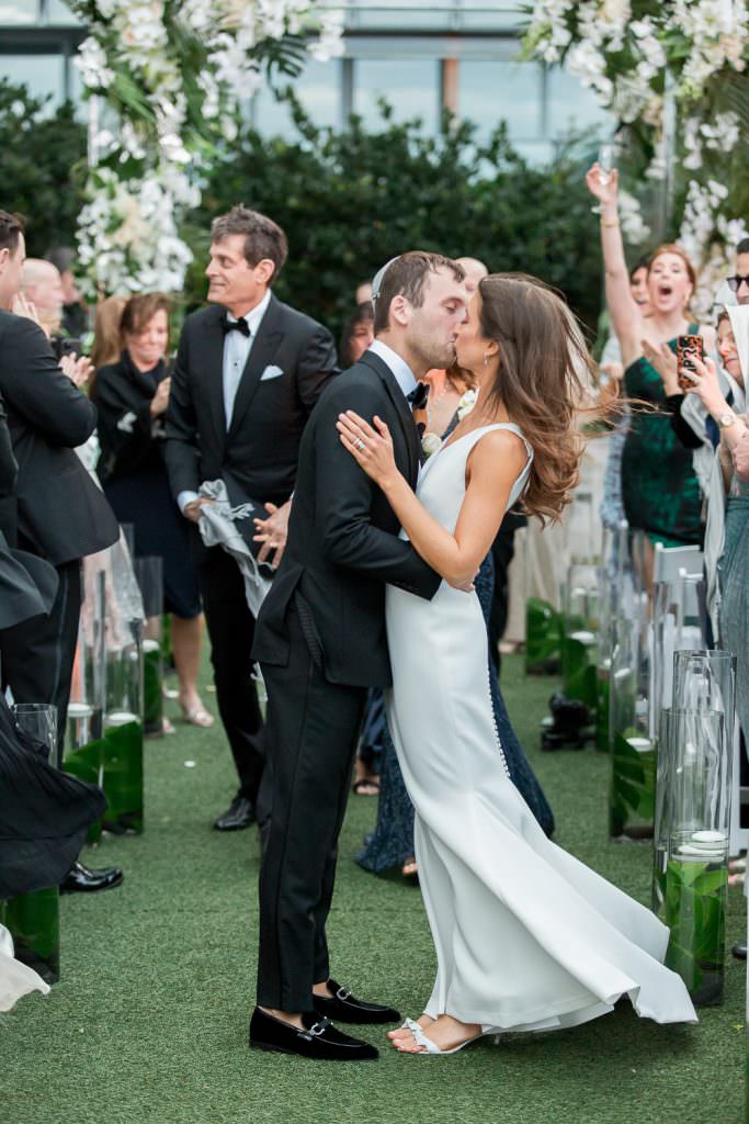 Bride and groom kiss at the end of aisle during their ceremony at the Edition on Miami Beach.