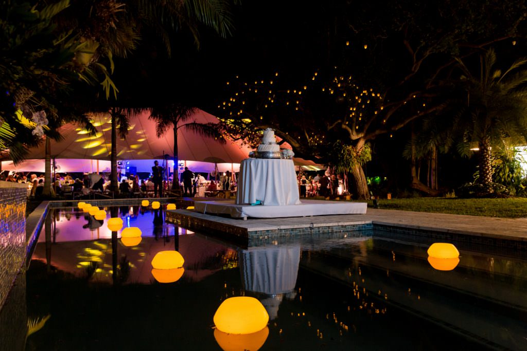 A wedding cake sits poolside during an at home wedding ceremony in Miam.