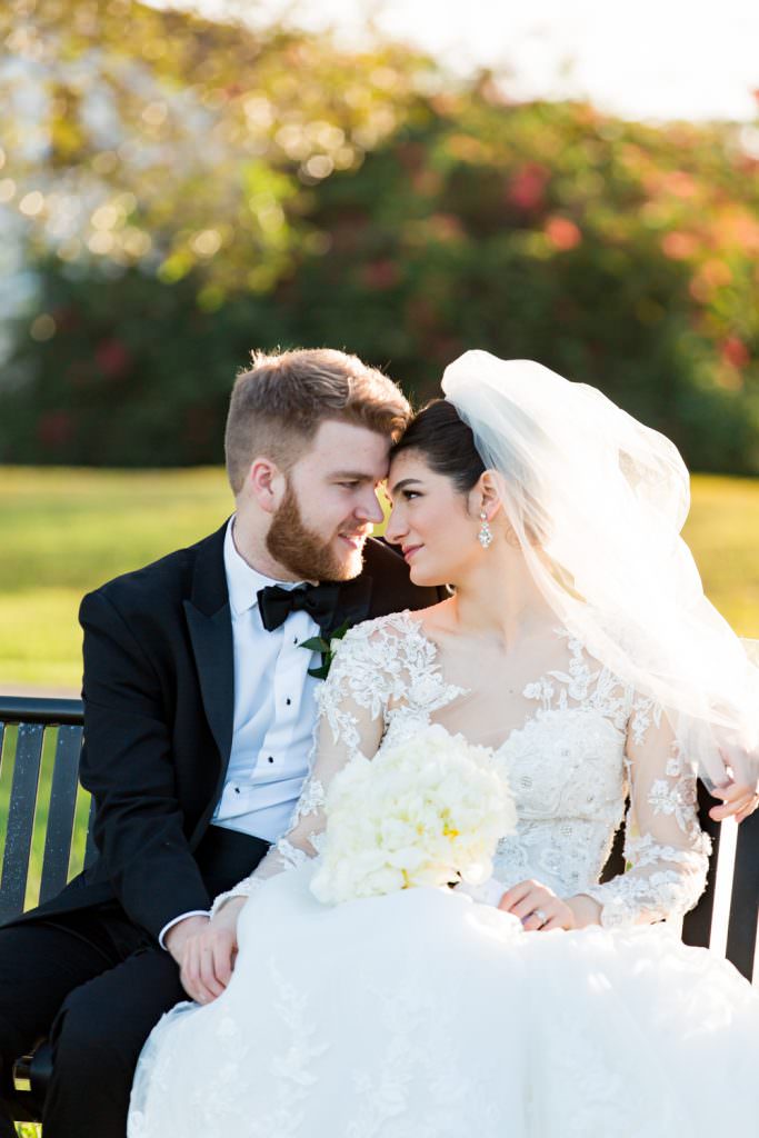 Bride and groom kissing on a park bench in the bride's backyard during their Palm Beach wedding.
