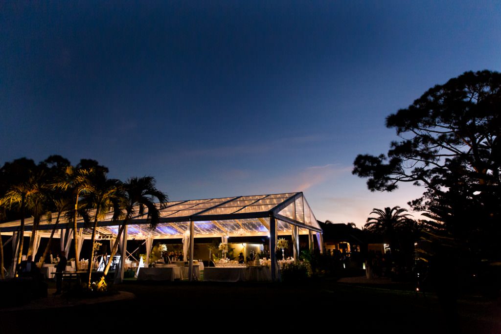 A tent is lit up in the bride's parents backyard.