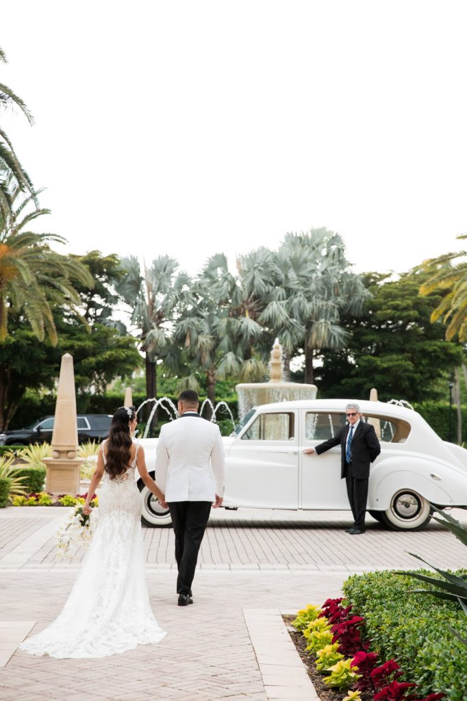 bride and groom walk towards their vintage wedding car at The Ritz-Carlton Key Biscayne