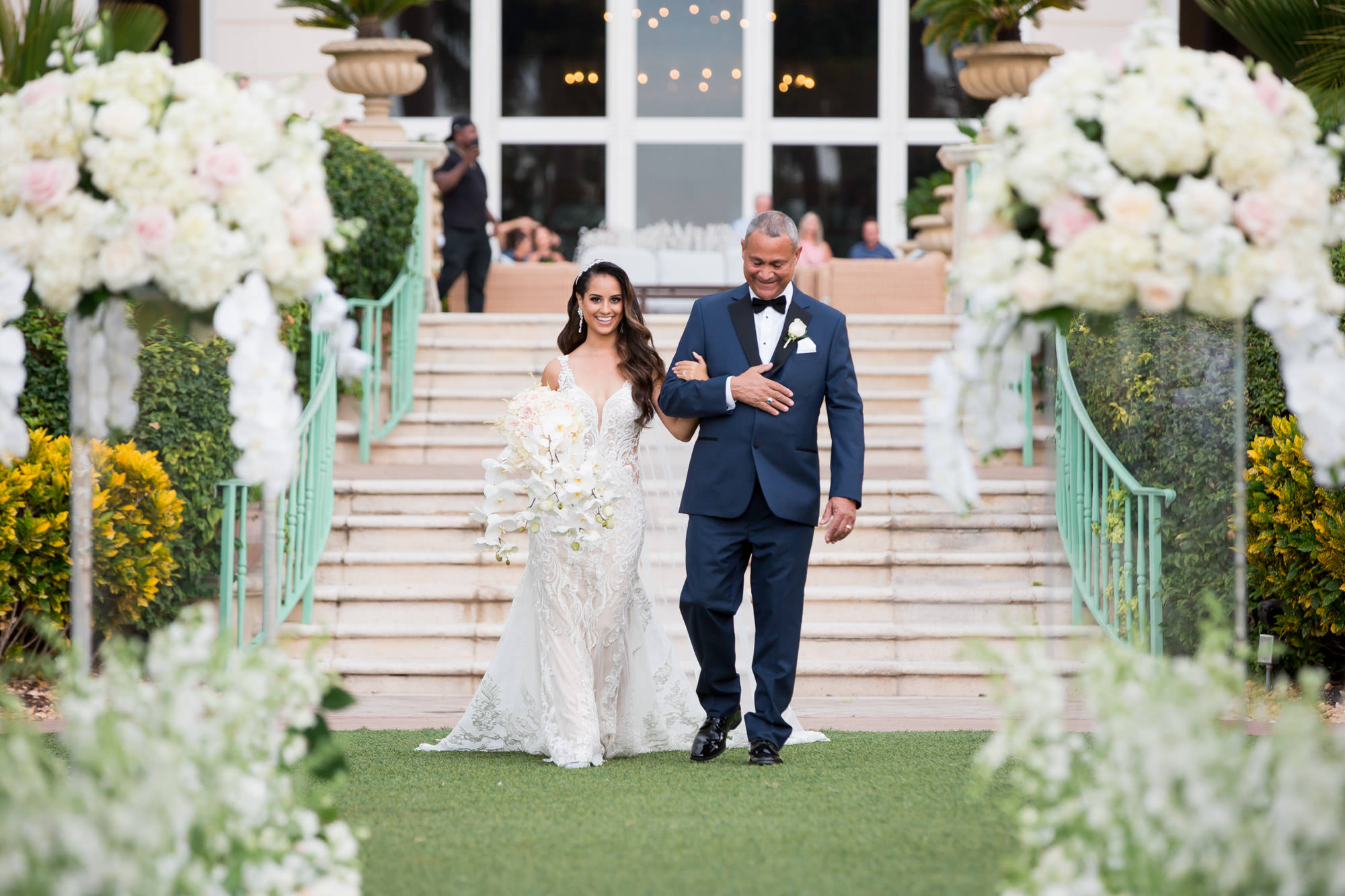 brides walks down the aisle arm in arm with her Dad to meet her groom