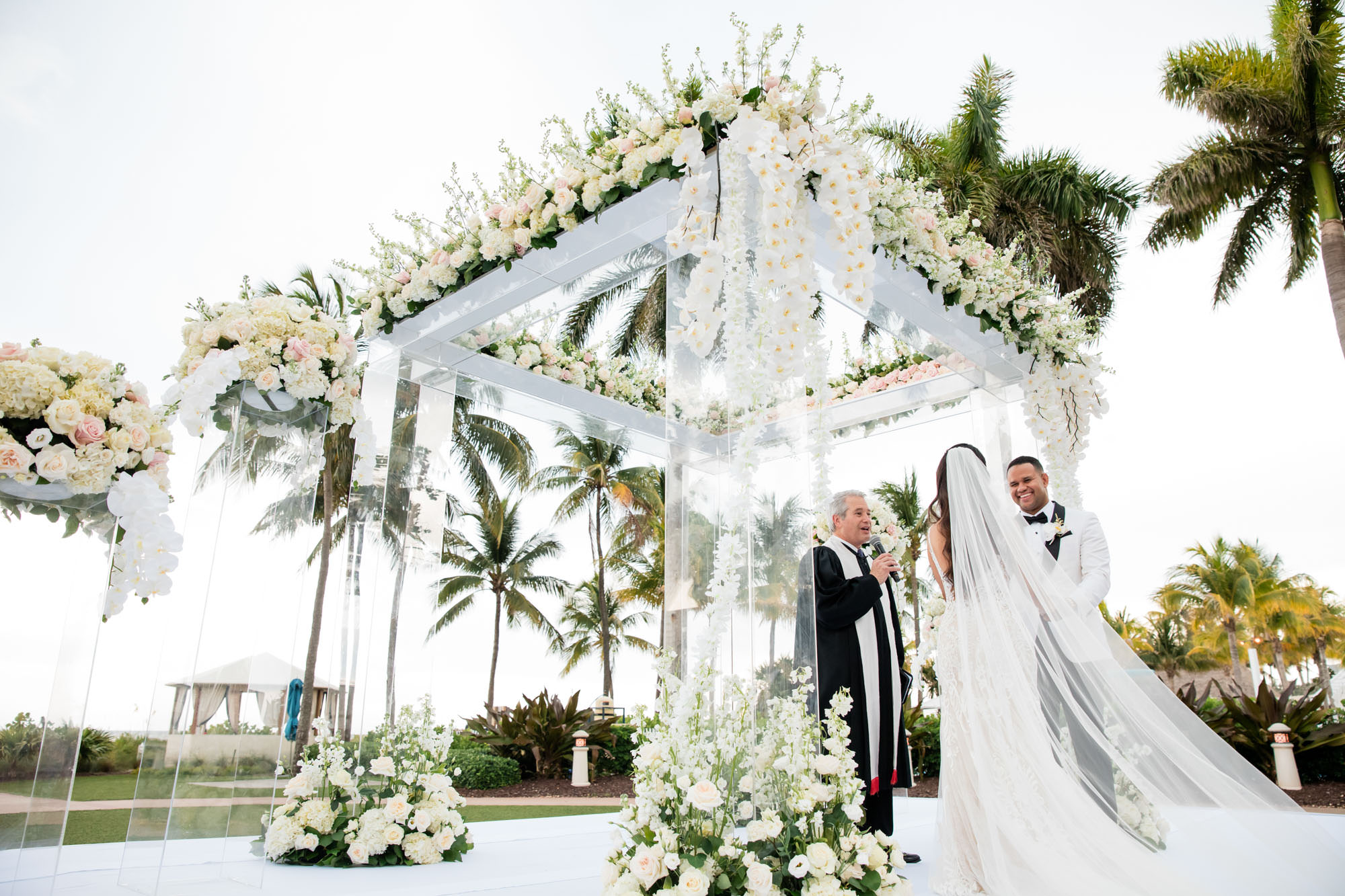 bride and groom exchange vows underneath florals on the ocean lawn