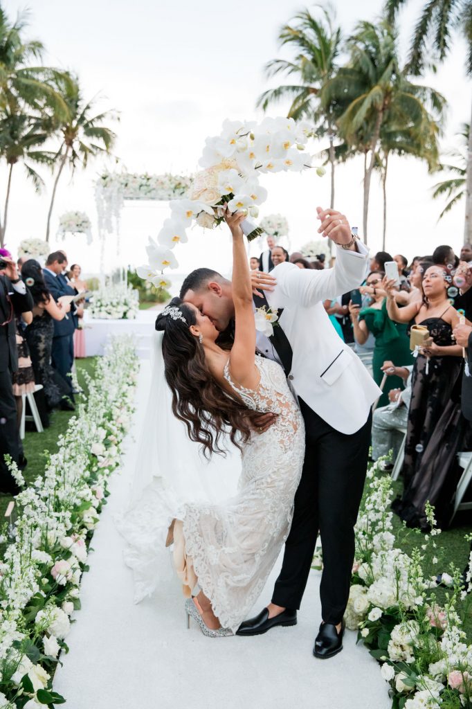 bride and groom walk back up the aisle together, stopping briefly to pose for guests cameras