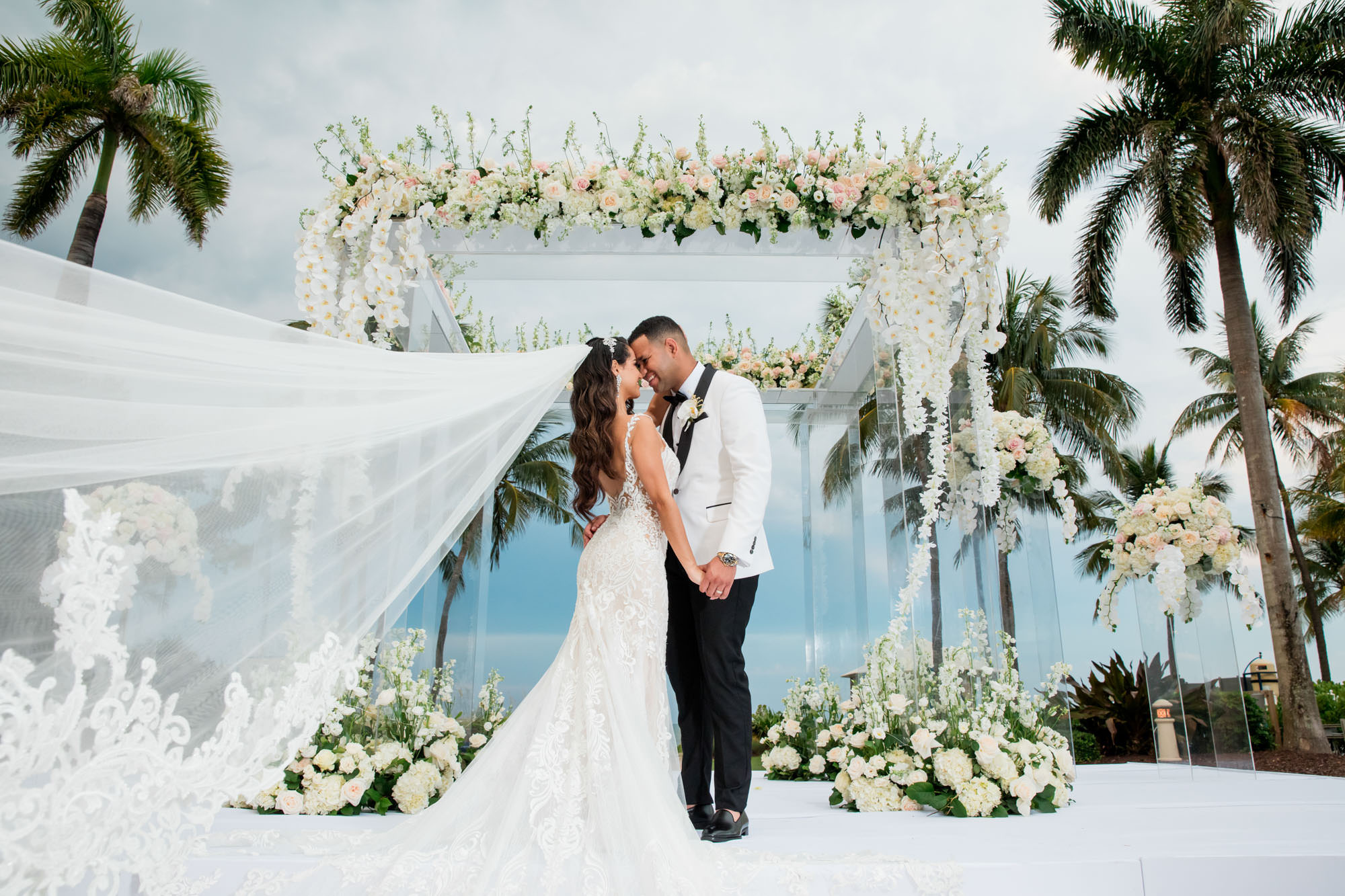 bride and groom have a portrait under a floral arch at their Ritz-Carlton Key Biscayne wedding