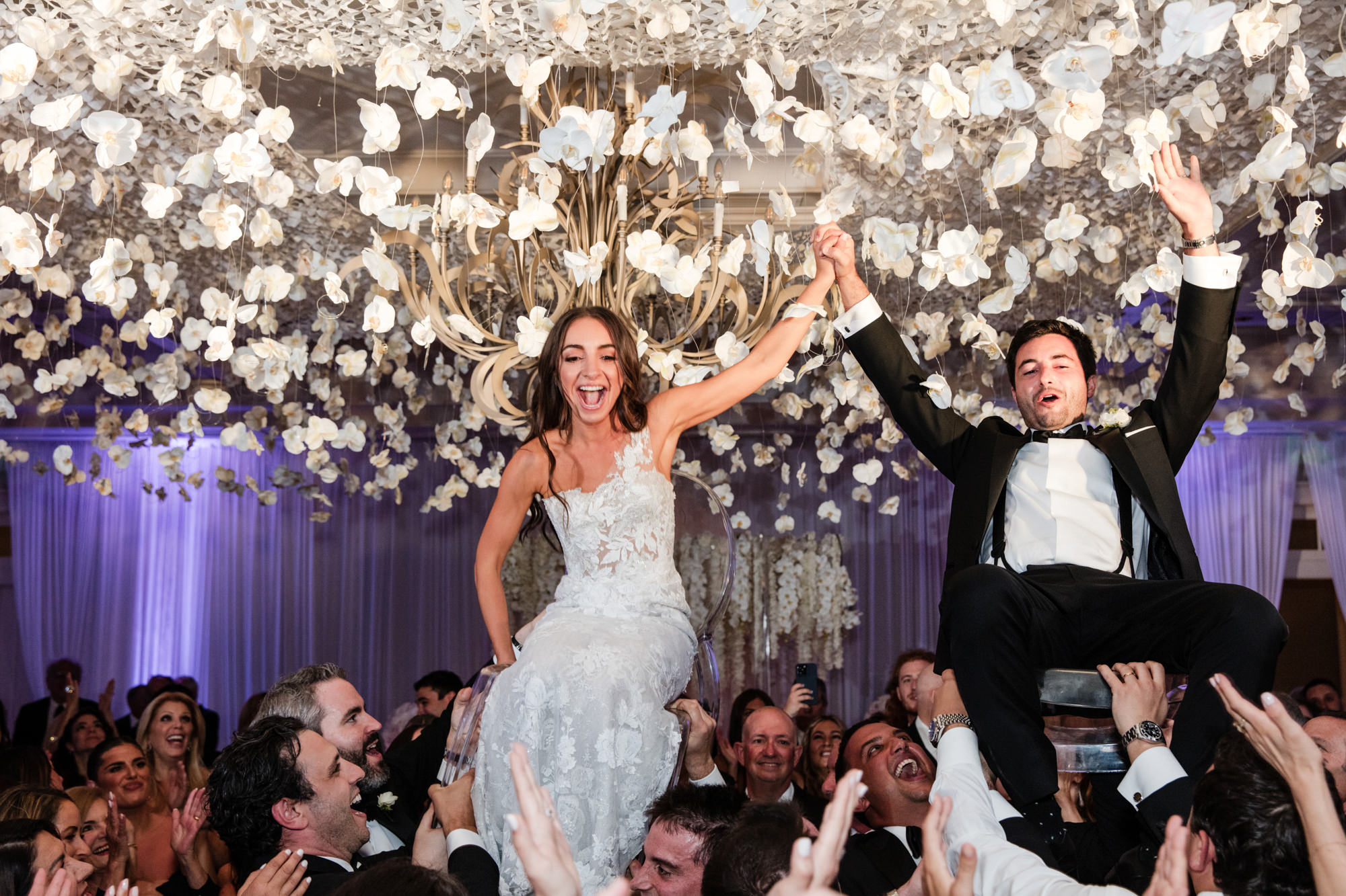 bride and groom are lifted up by guests after their wedding dance
