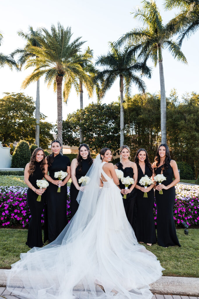 Bride surrounded by bridesmaids in classic black dresses before the ceremony at the Polo Club