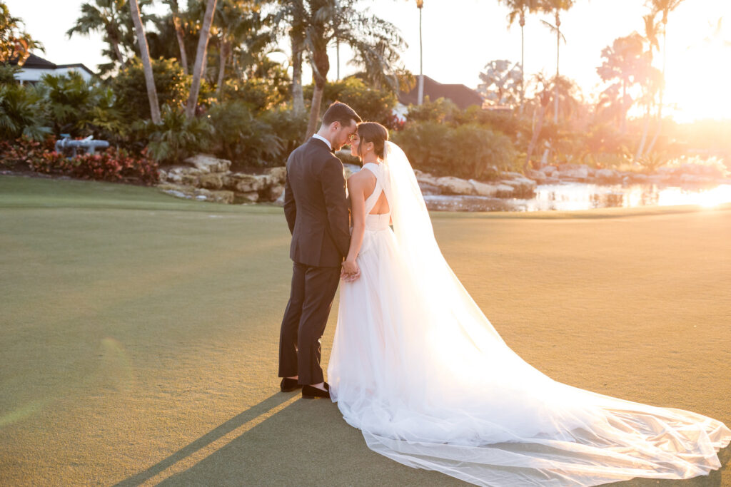 Bride and groom walking together on the Polo Club golf course at sunset in Boca Raton