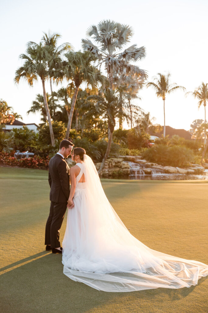 Bride and groom silhouetted against the sunset on the Polo Club golf course.