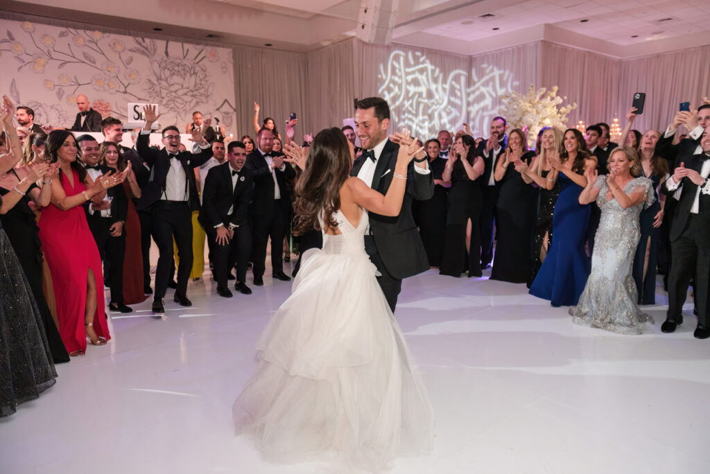 Bride and groom sharing their first dance surrounded by guests at the Polo Club reception