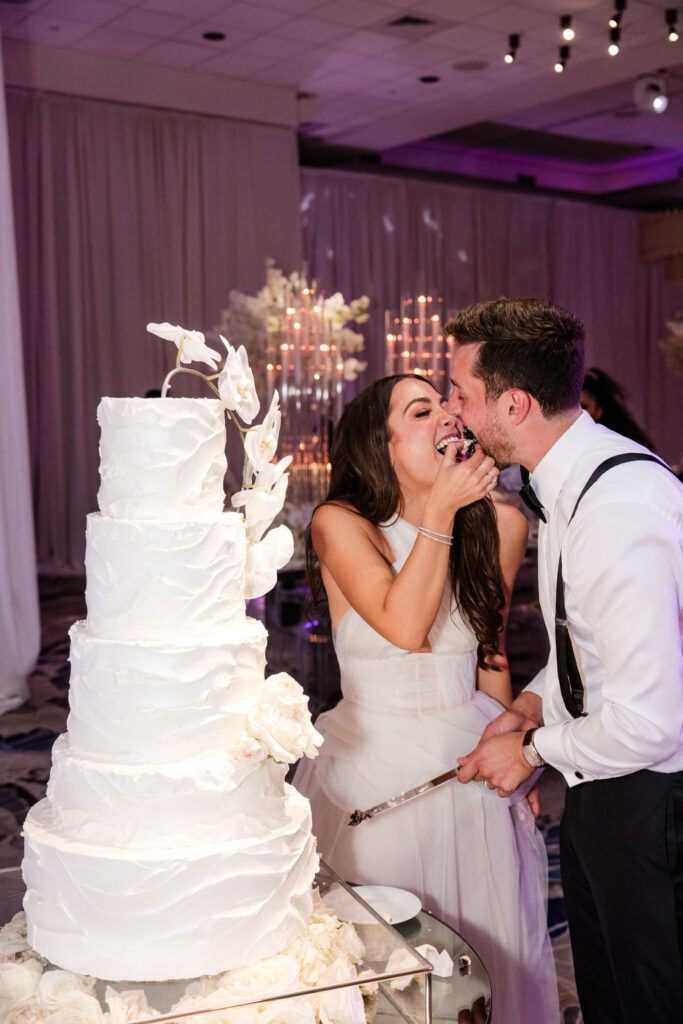 Close-up of couple laughing while cutting their wedding cake at the Polo Club