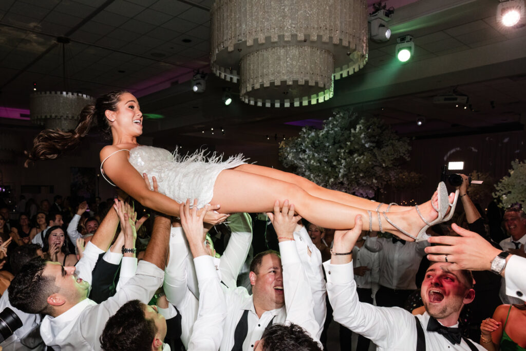 Guests lifting the couple during crowd surfing moment at wedding reception