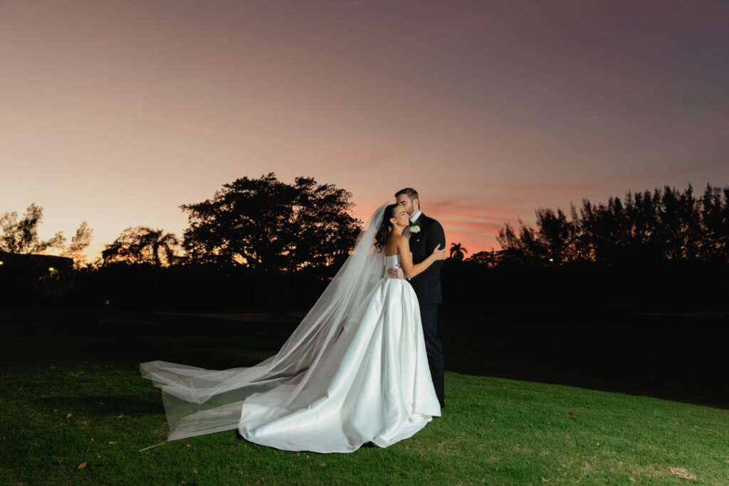 Bride and groom walking together along the golf course during sunset at Royal Palm Yacht Club in Boca Raton