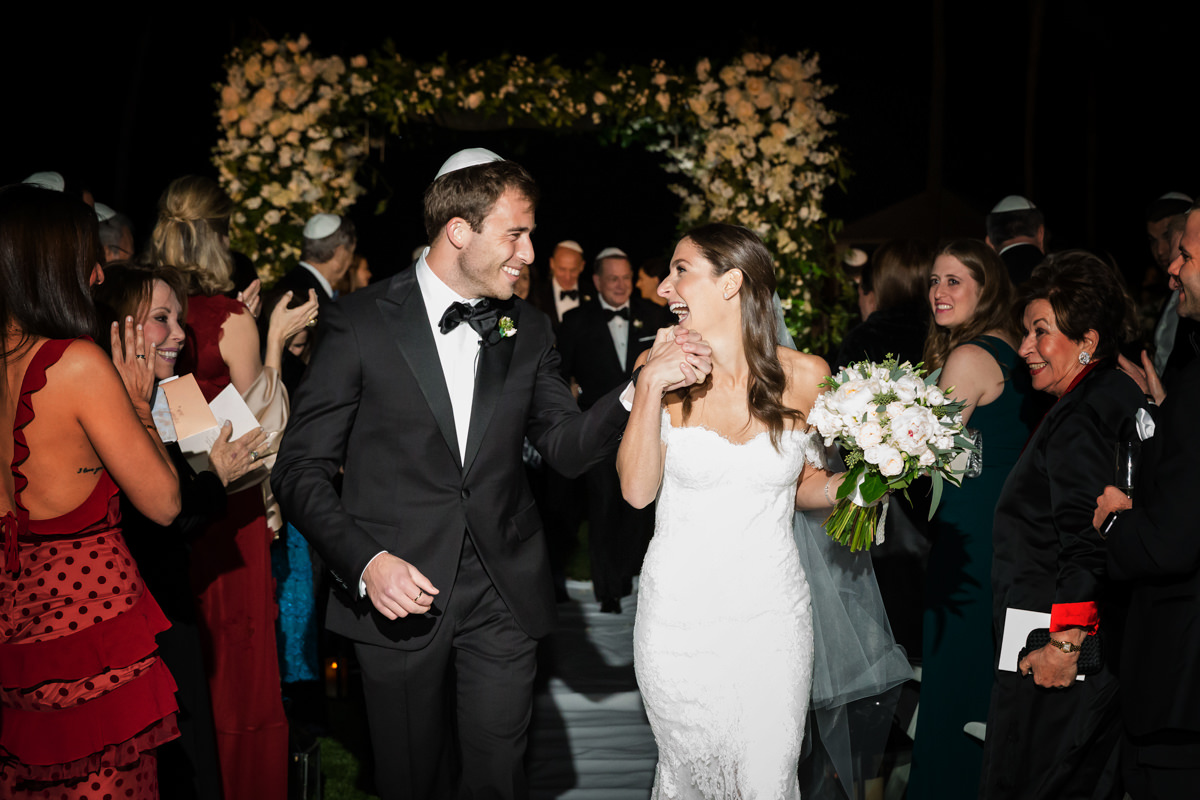 Couple walks down the aisle smiling during their wedding at the Ritz Carlton in Key Biscayne.