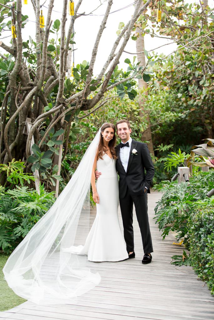 A couple posing on the board walk at the Edition during their wedding day.