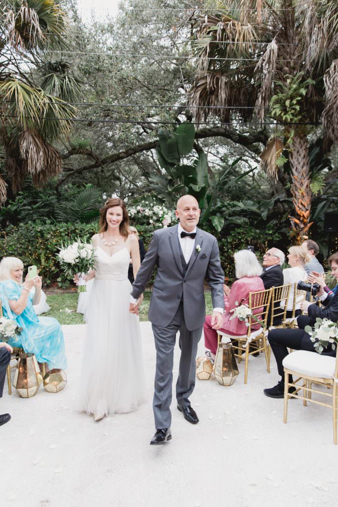 A bride and groom walk down the aisle after their wedding ceremony at home in Miami.