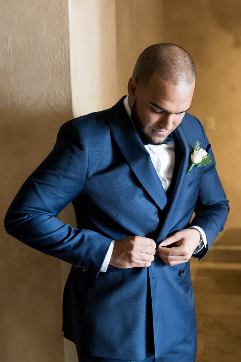 Groom buttons his blue tuxedo jacket during his wedding at the Biltmore hotel.