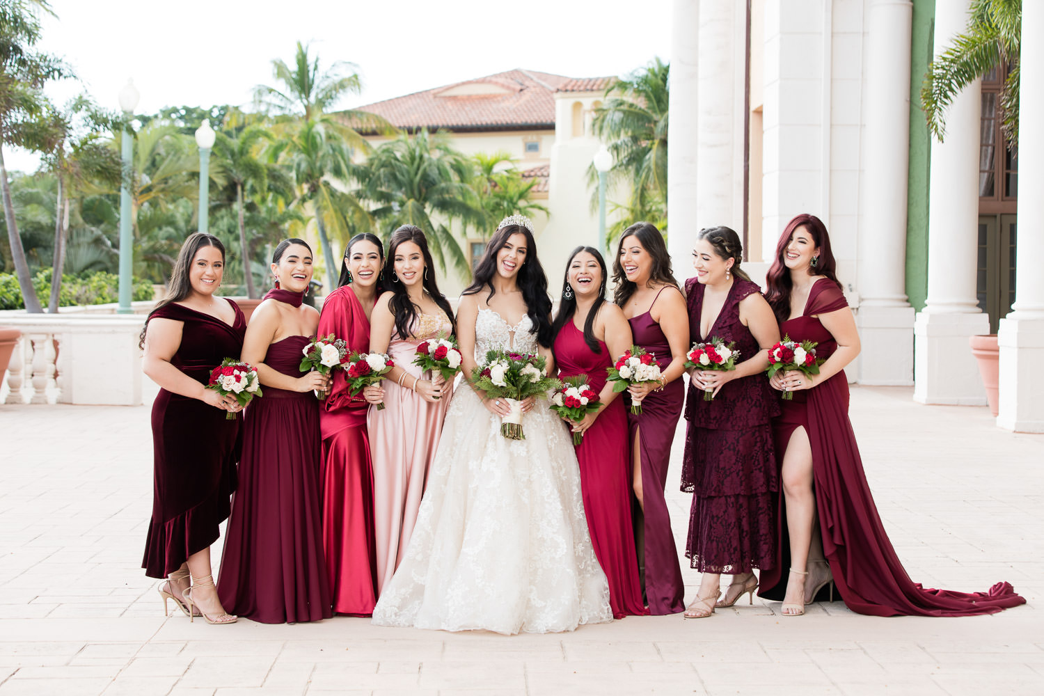 Bridesmaids, wearing crimson wedding gowns, pose with a bride during a wedding ceremony at the Biltmore hotel.