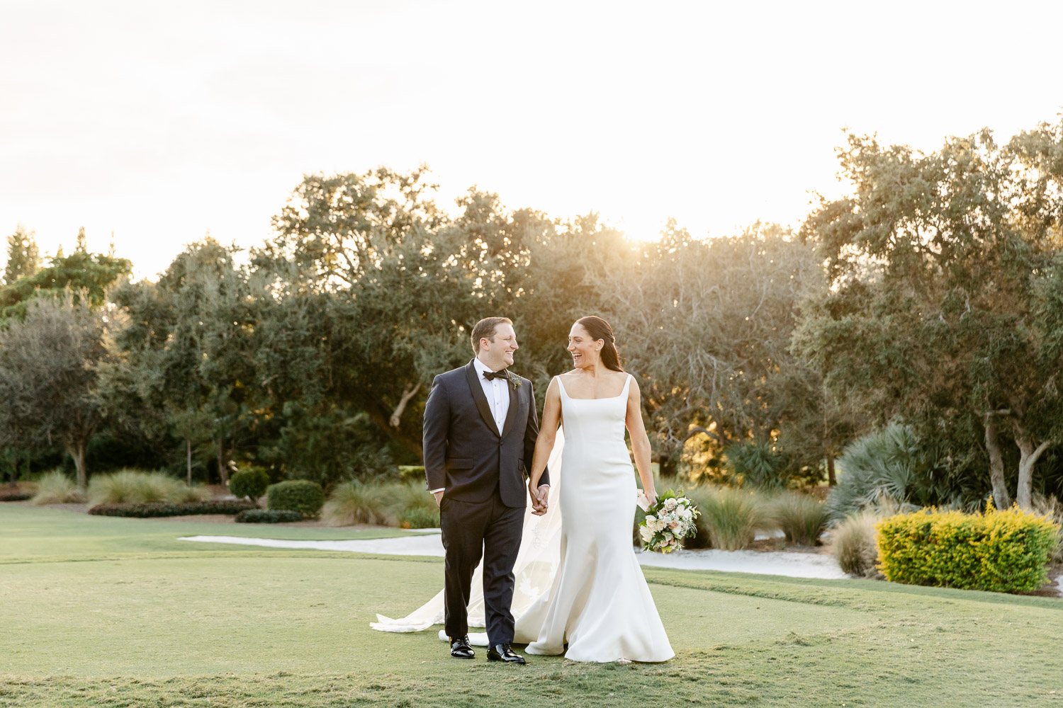 Bride and groom walking on a golf course at sunset in Palm Beach.