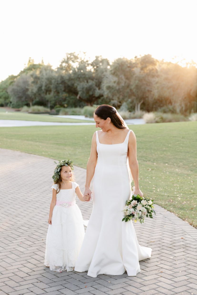 Flower girl looking at bride during her wedding on a golf course in Palm Beach.