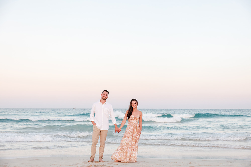 A couple holding hands on the beach at South Pointe Park.