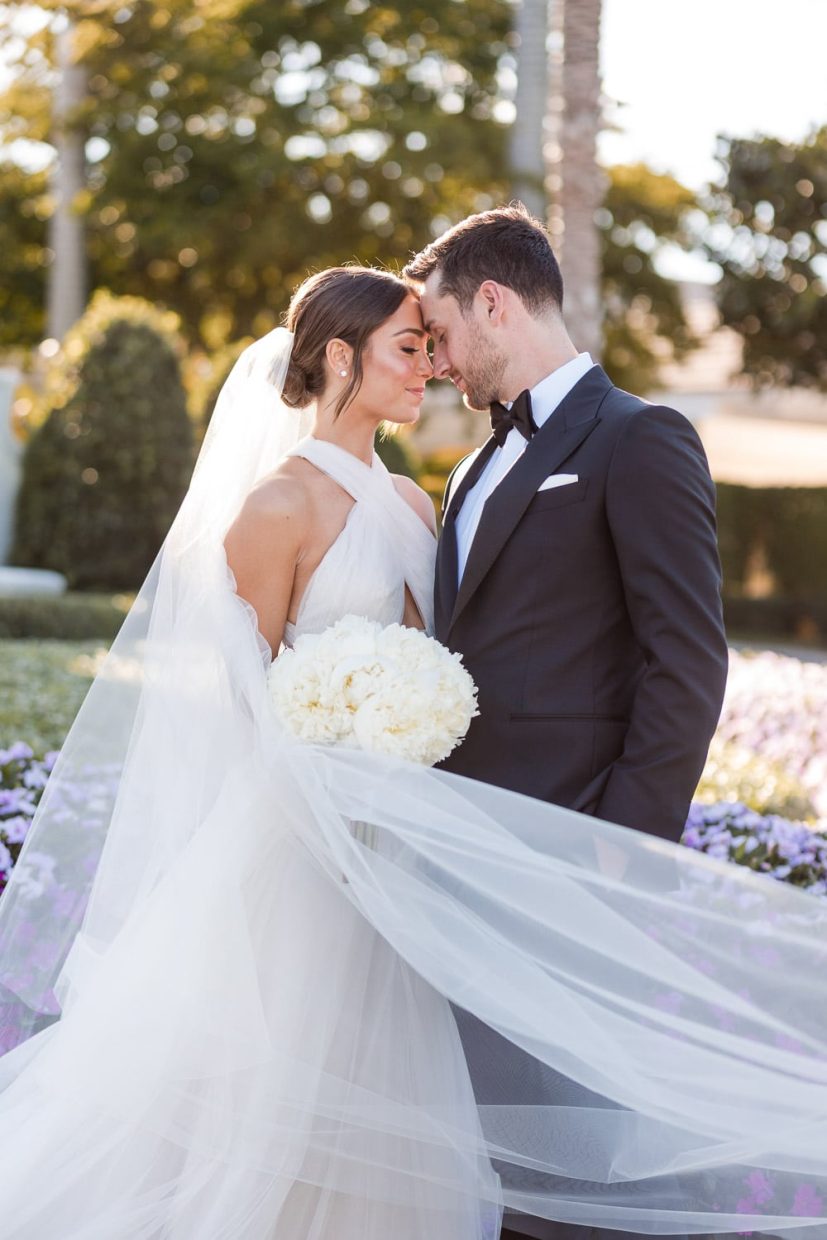 Bride and groom pose for a portrait in front of the Polo Club in Boca Raton.