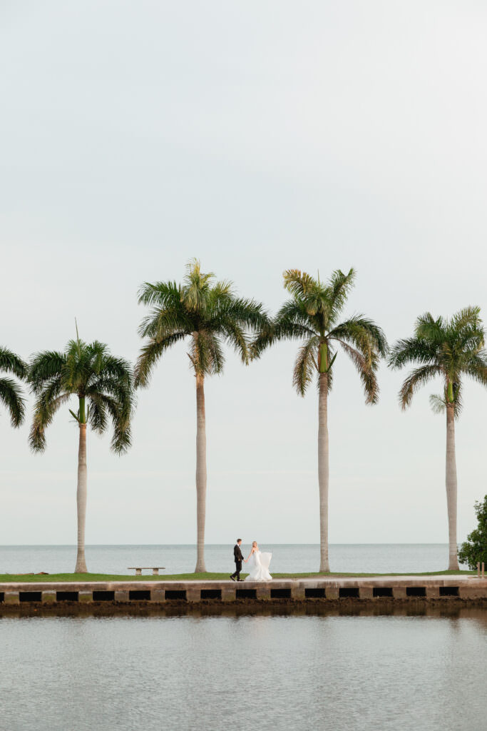Allie and Eric walking together along the Deering Estate waterfront at sunset