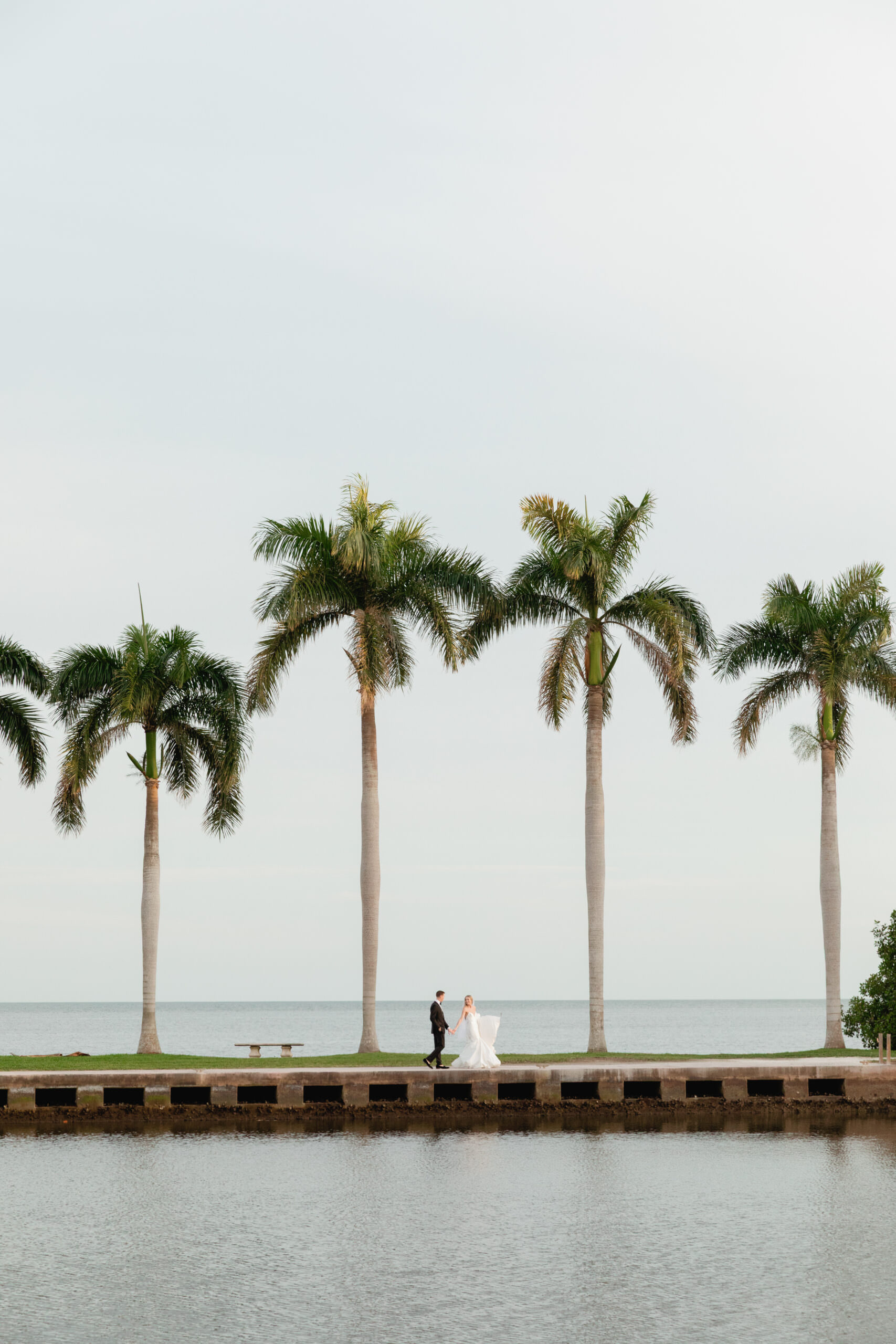 Allie and Eric walking together along the Deering Estate waterfront at sunset