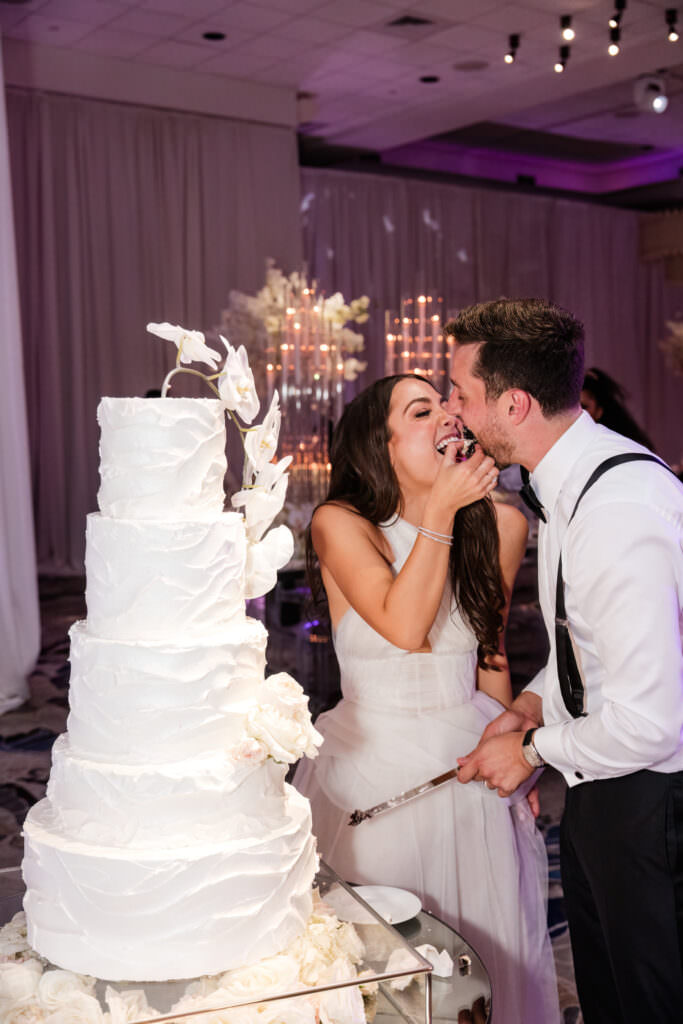 Close-up of couple laughing while cutting their wedding cake at the Polo Club