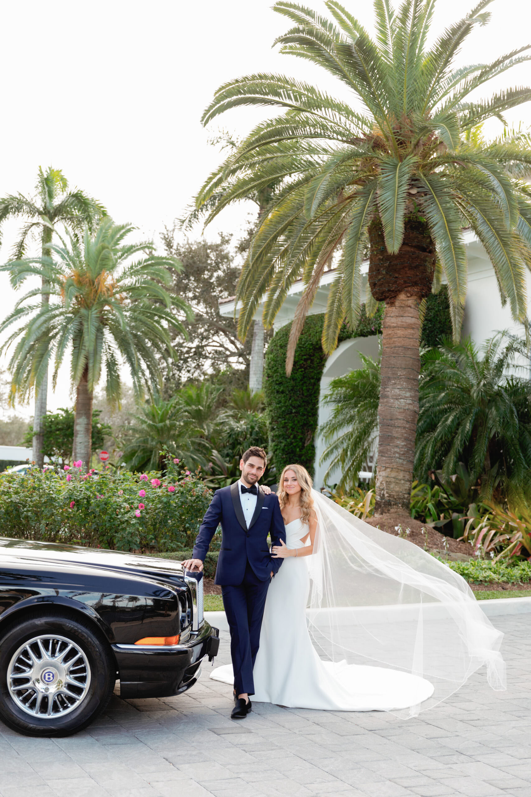 Bride and groom sharing a quiet moment beside a vintage black getaway car at Woodfield Country Club in Boca Raton