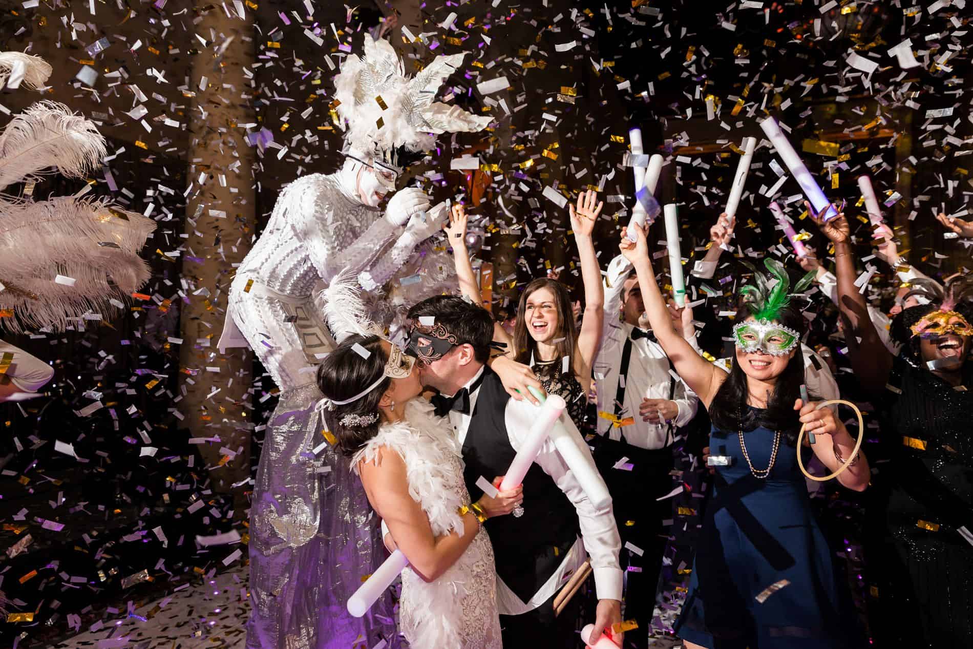 Guests celebrating with confetti and party props, joyful expressions, lively atmosphere, indoor event.