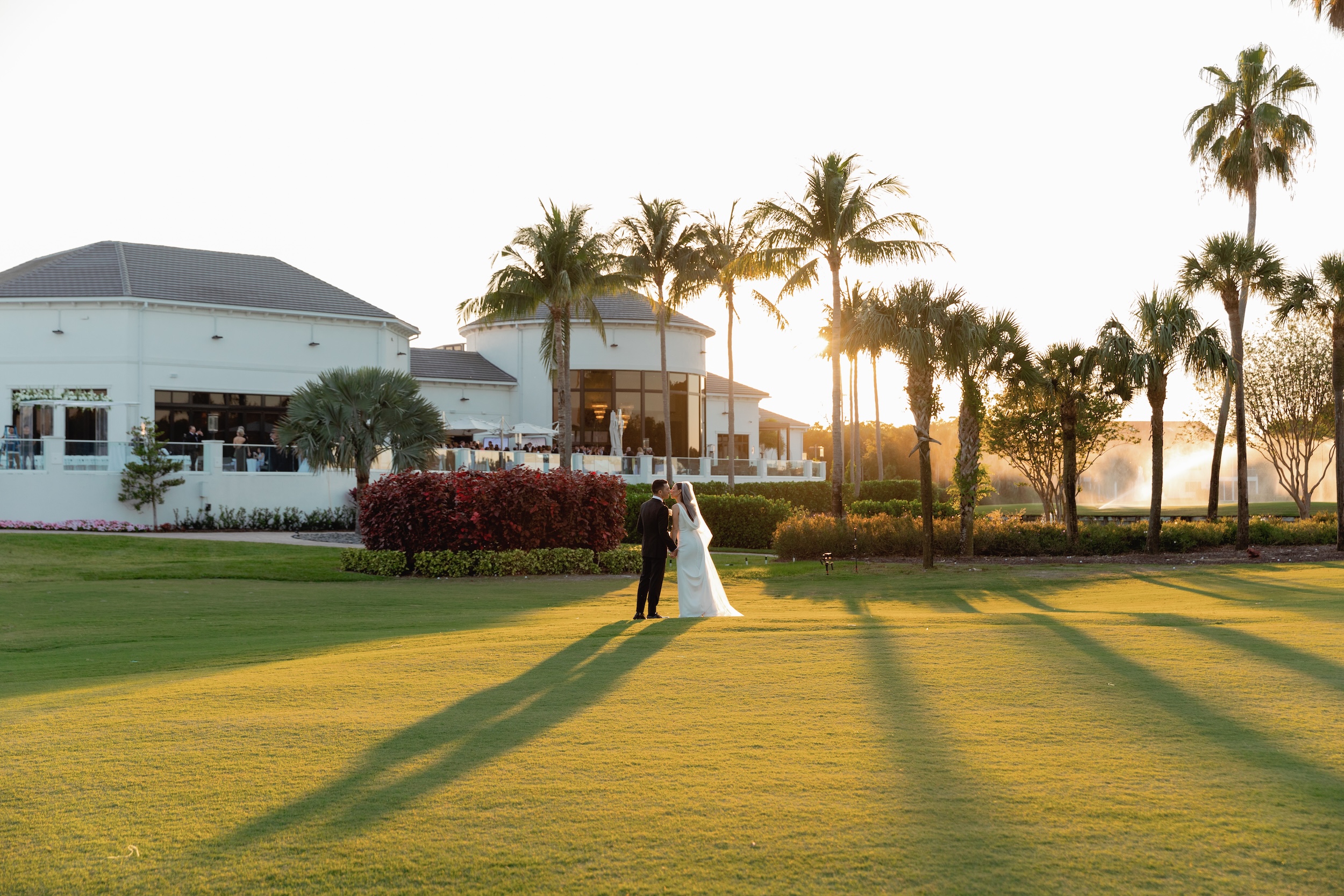 Bride and Groom Kiss at Sunset on Lawn of Broken Sound Club