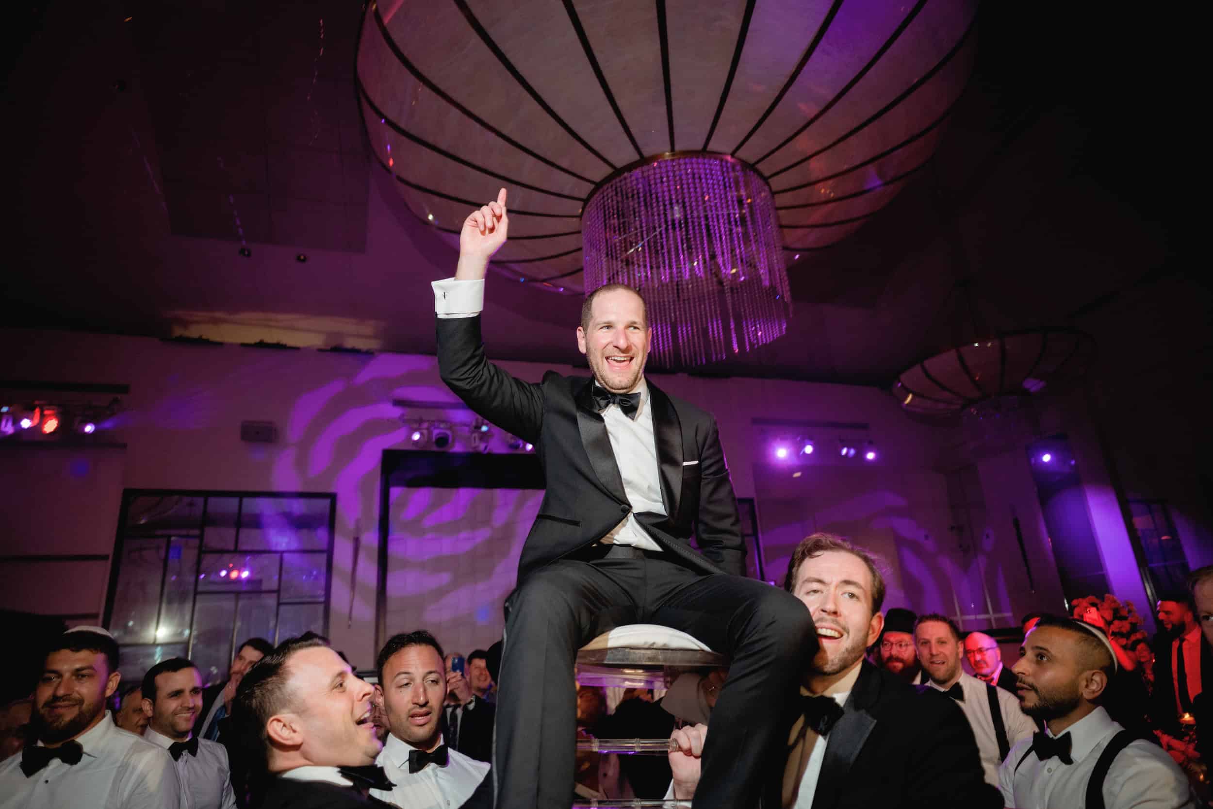 Groom Lifted on Chair at Hora During Jewish Wedding