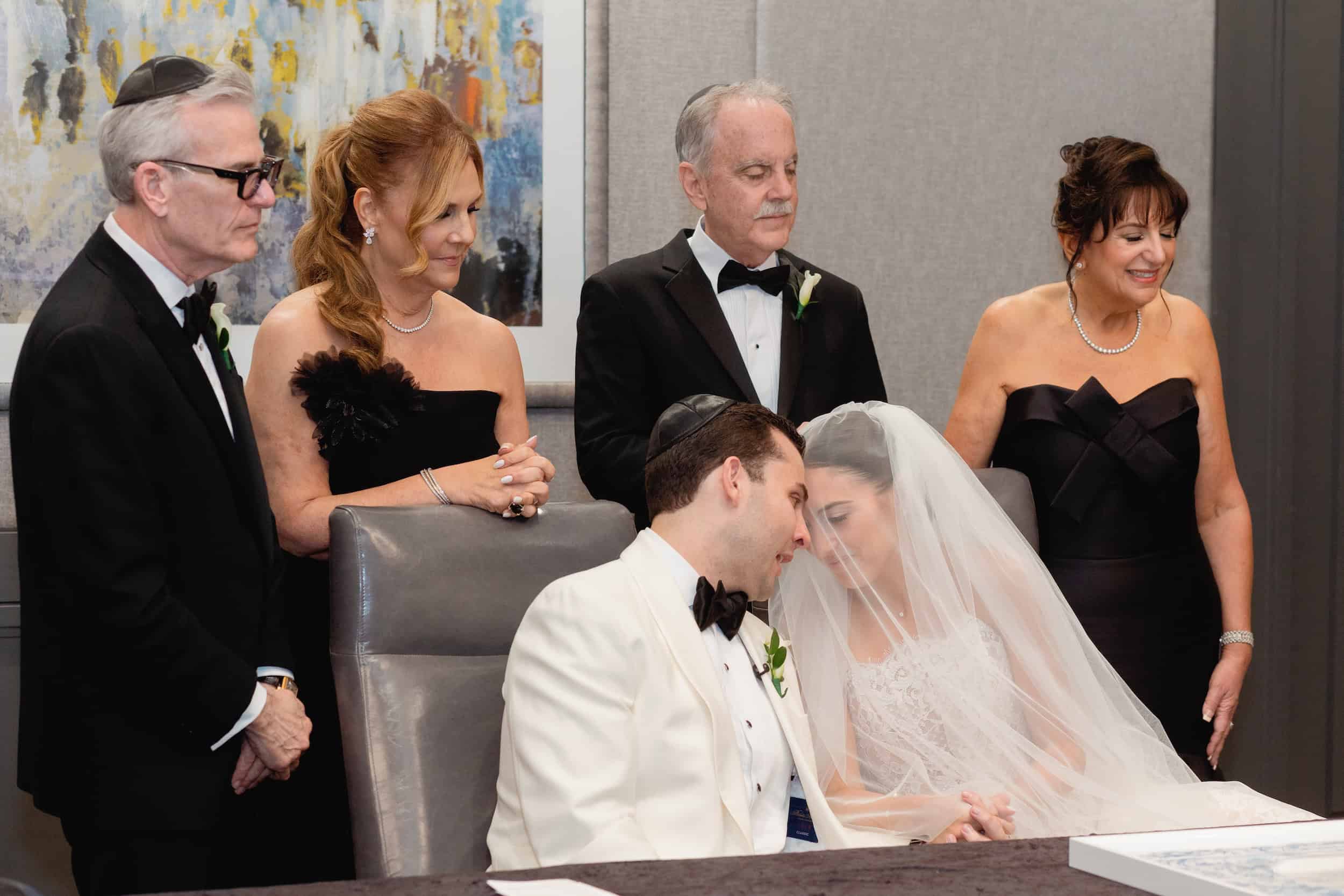 Bride and groom share a tender moment with family during a wedding ceremony, emotional and intimate setting.