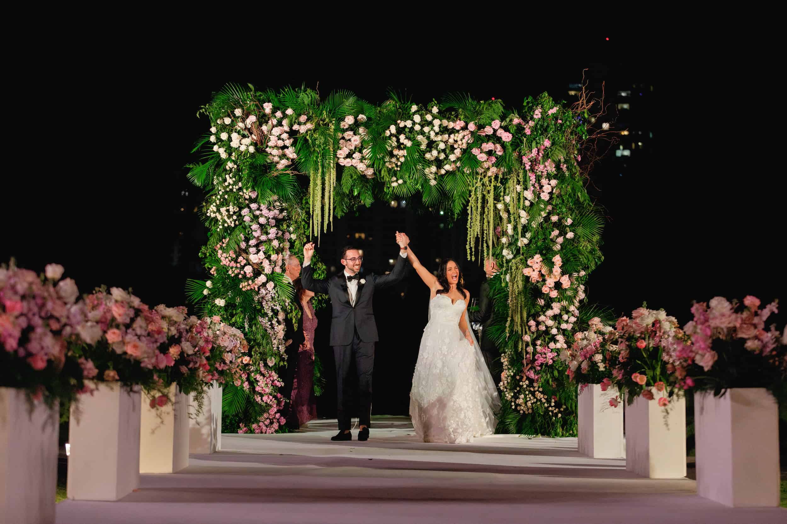 Bride and groom holding hands and smiling as they walk down the aisle at their wedding ceremony.