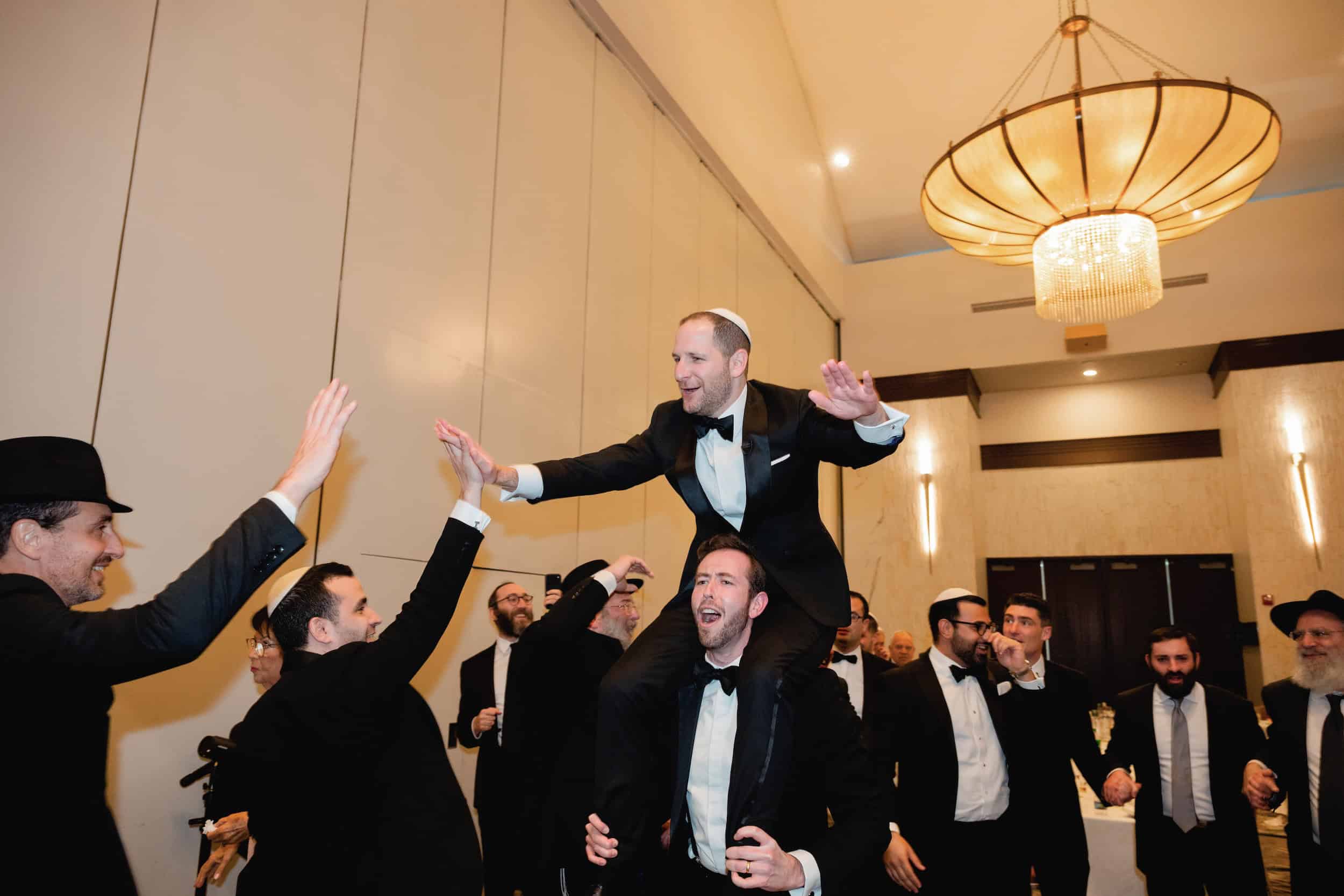 Groom on Shoulders of Man of Honor at Jewish Wedding
