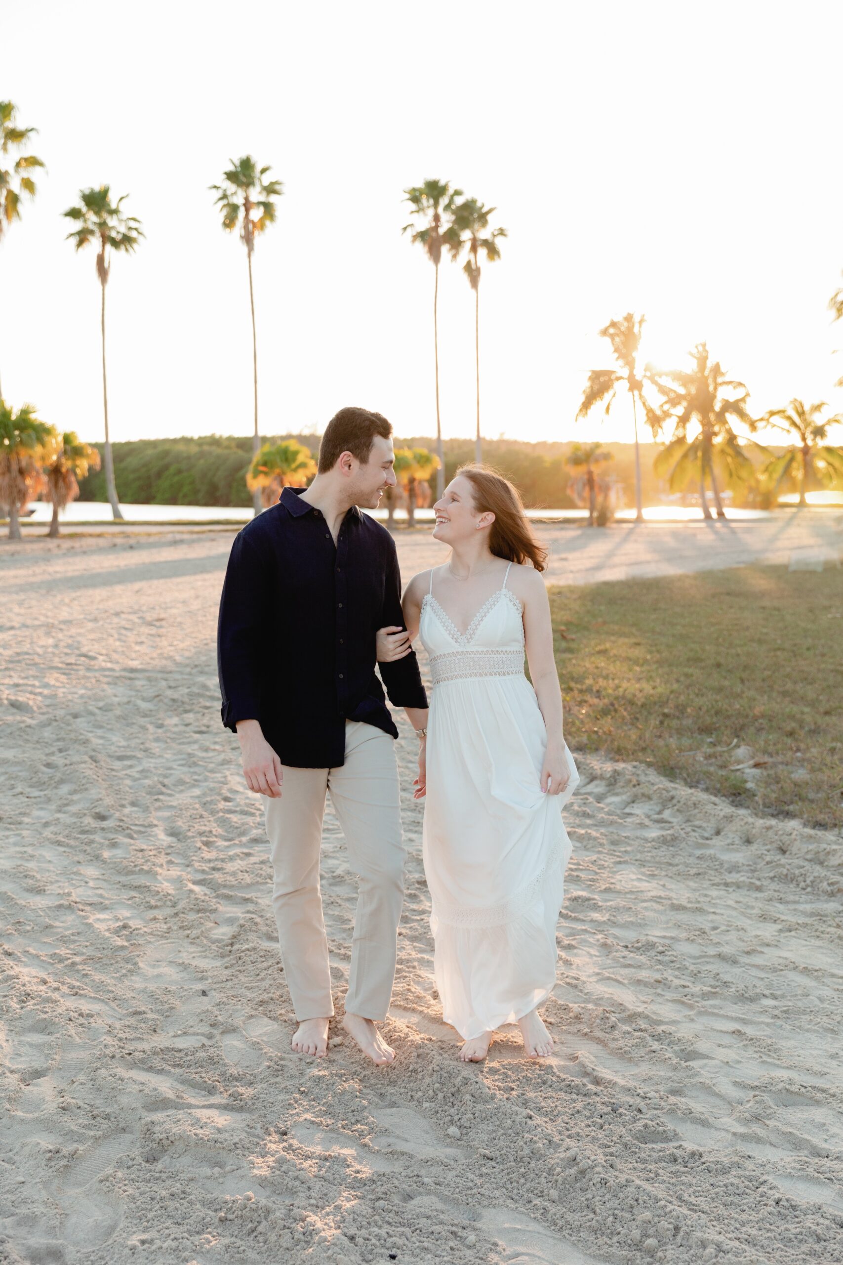 Couple Links Arms, Walks Through Matheson Hammock Park Barefoot During Engagement Photoshoot