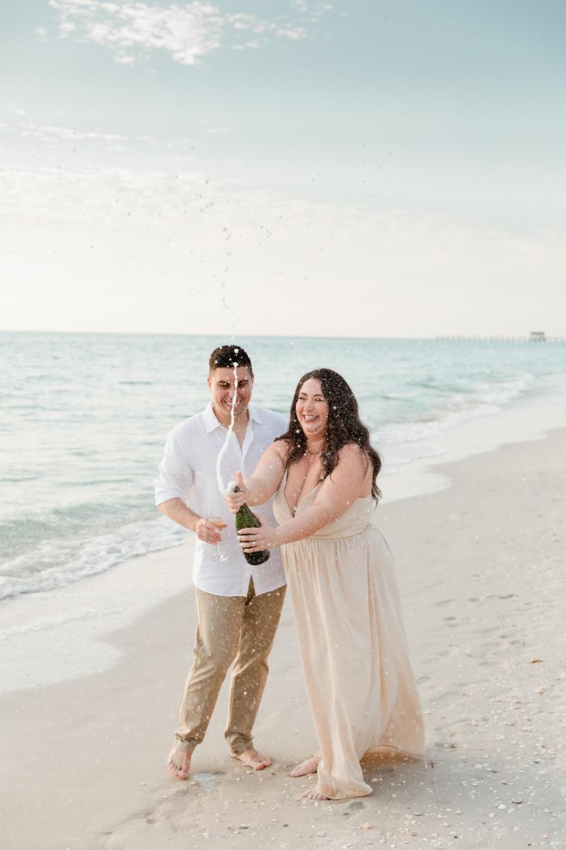 Engaged Couple Pops Bottle of Champagne on Beach in Naples, FL