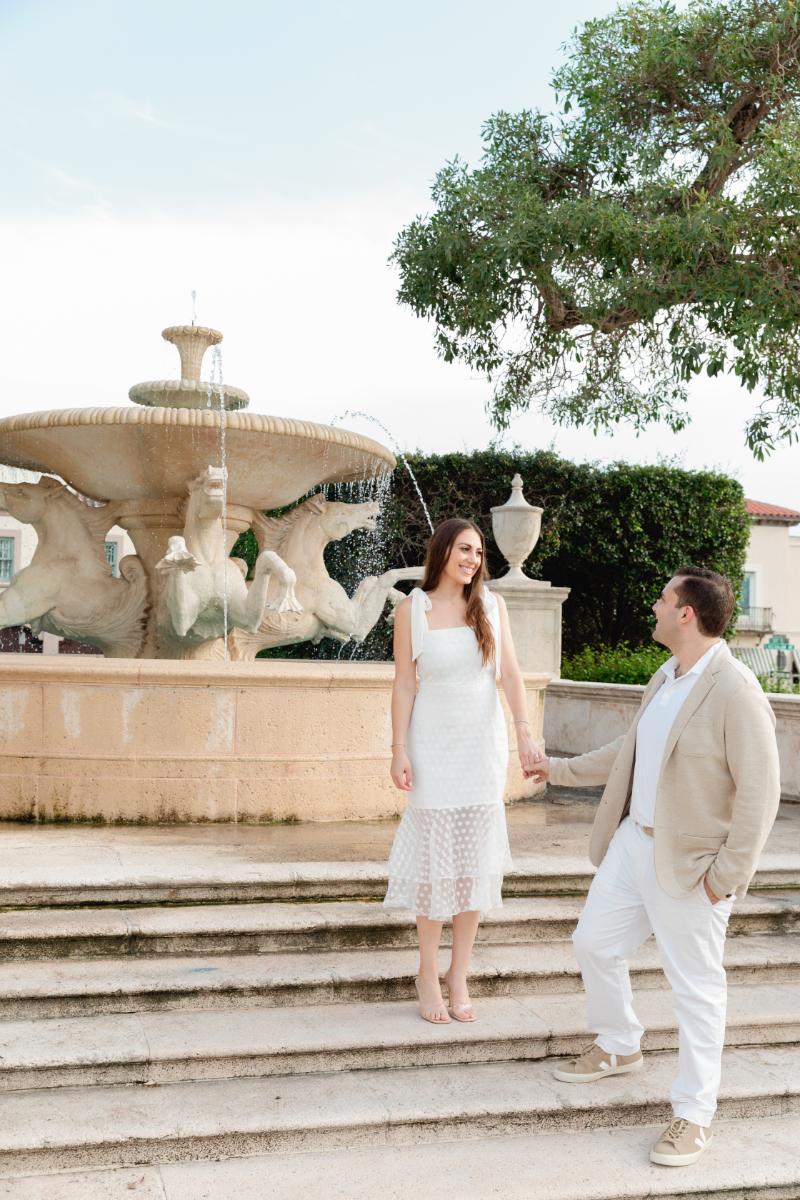 Man Takes Hand of Fiance, Guides her Down Stairs of Stone Fountain in Palm Beach