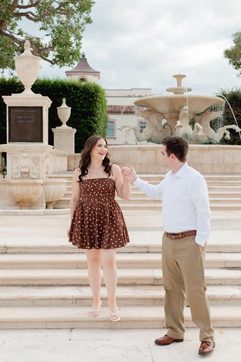 Man Takes Hand of Fiance, Guides her Down Stone Steps in Palm Beach
