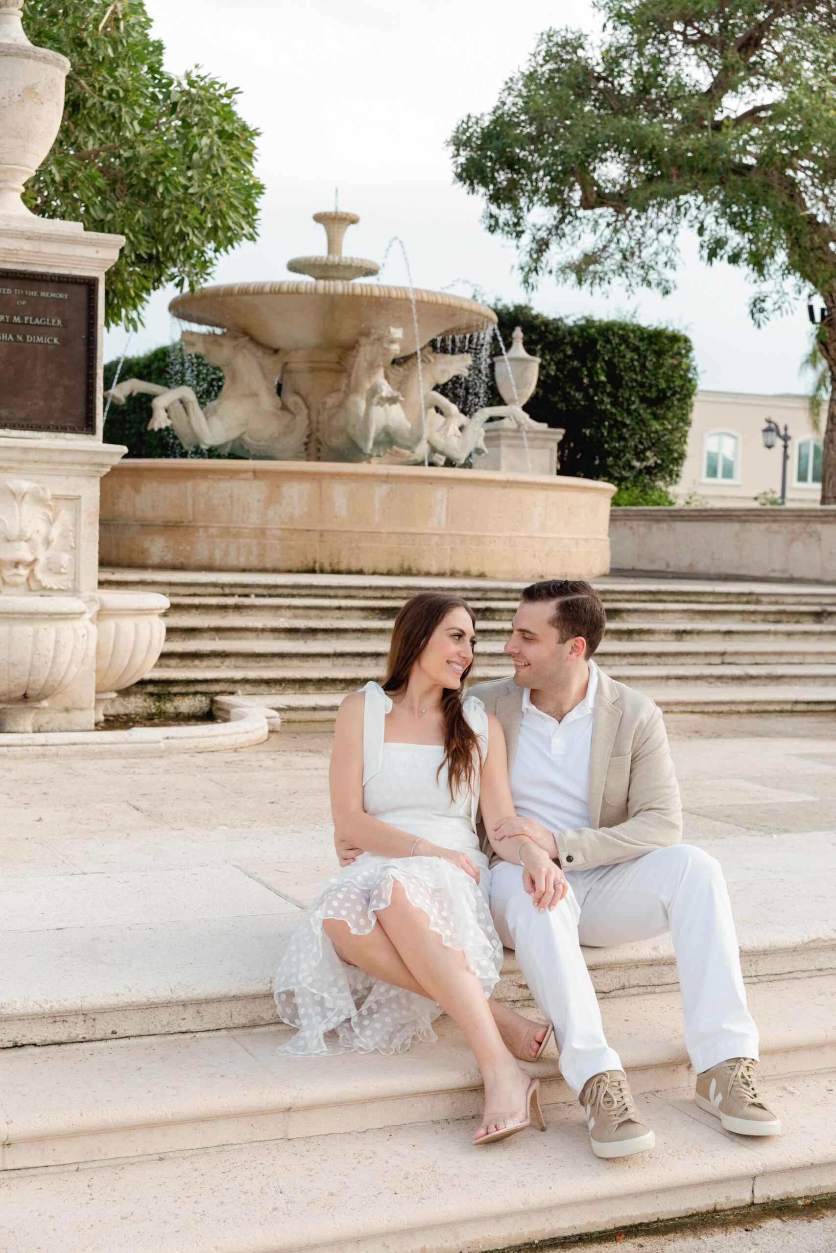 Engaged Couple Sits of Stone Stairway of Fountain on Worth Avenue